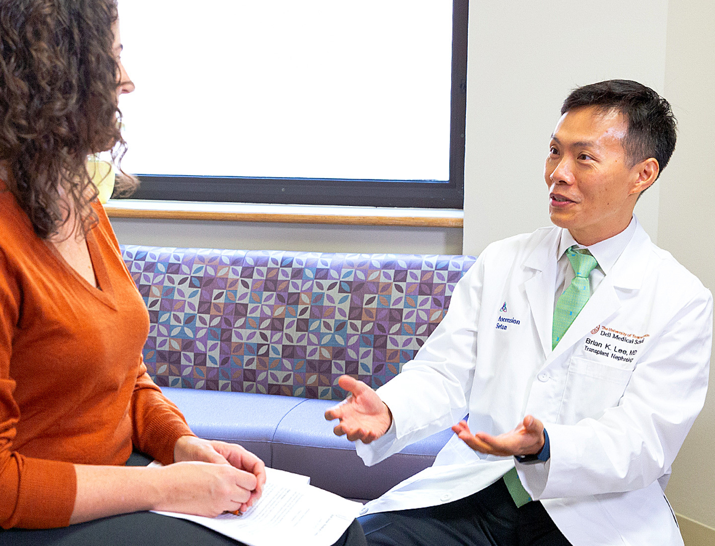 A patient is seated in an exam room with transplant surgeon Brian Lee, MD who is discussing the visit.