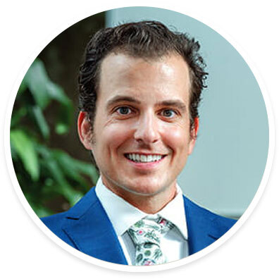 Headshot of Dr. Aaron Laviana smiling in a blue suit jacket with a white shirt and floral-patterned tie.