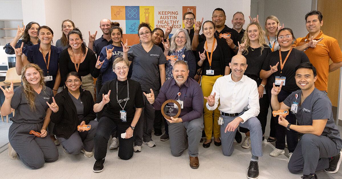 UT Health Austin Musculoskeletal Institute care team poses with Bevo Award, making Hook ’em Horns hand gestures.