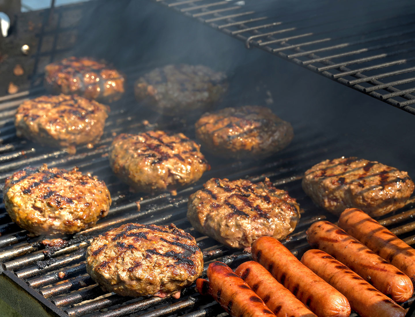 Hamburgers and hot dogs being cooked on a grill