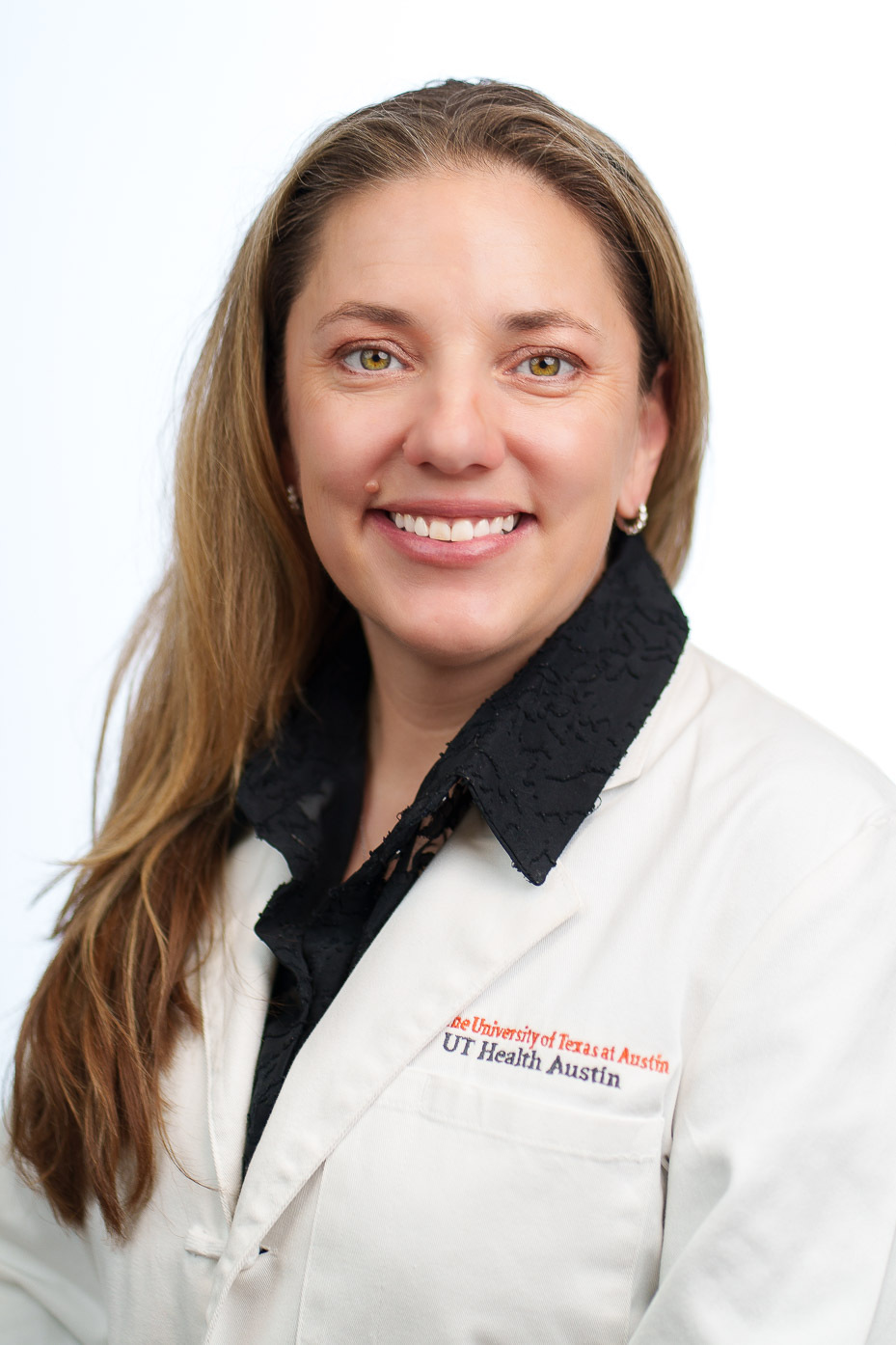 Chesney Castleberry is smiling at the camera. She is wearing a black collared shirt under a white coat.